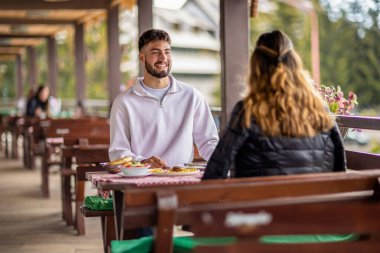 Genç bir çift dışarıda, dağlarda yemek yiyor.