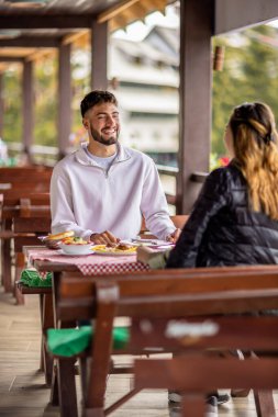 Genç bir çift dışarıda, dağlarda yemek yiyor.