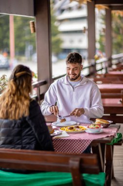 Dağlarda açık havada yemek yiyen çift.