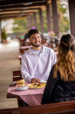 Genç bir çift dışarıda, dağlarda yemek yiyor.