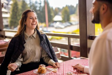 Genç bir çift, bir dağ restoranının terasında krema dolu profiterollerin tadını çıkarıyor.