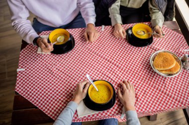 Bir dağ restoranının terasında, ahşap bir masada servis edilen üç kase sıcak çorba. 