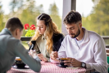 Erkek ve kız kardeş birlikte bir dağ restoranının terasında öğle yemeği yiyorlar açık bir bahar ya da sonbahar gününde..