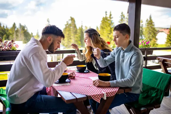 Erkek ve kız kardeşler açık bir bahar ya da sonbahar gününde bir dağ restoranının terasında öğle yemeği yiyorlar.. 