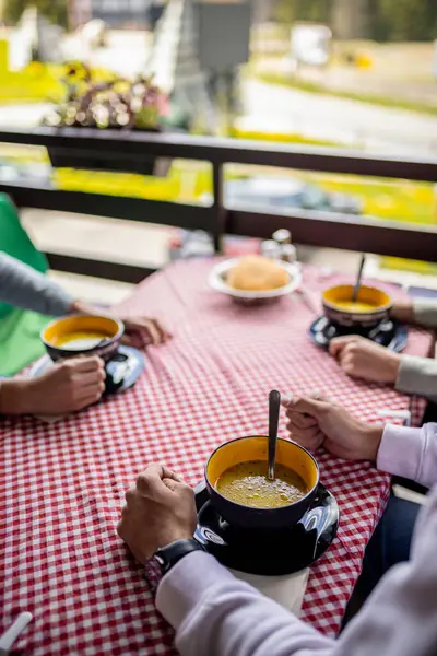 Bir dağ restoranının terasında, ahşap bir masada servis edilen üç kase sıcak çorba. 