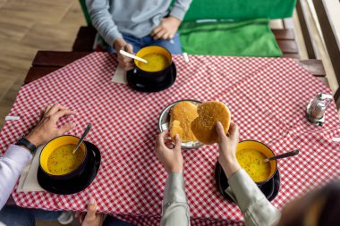 Bir dağ restoranının terasında, ahşap bir masada servis edilen üç kase sıcak çorba. 