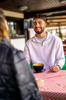 Genç çift, güneşli bir sonbahar ya da bahar günü birlikte bir dağ restoranının terasında öğle yemeği yiyorlar..