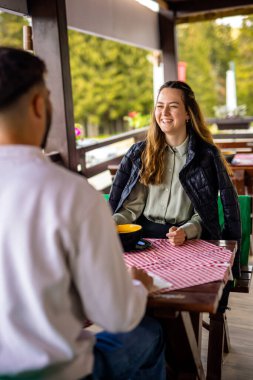 Genç çift, güneşli bir sonbahar ya da bahar günü birlikte bir dağ restoranının terasında öğle yemeği yiyorlar..
