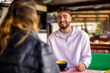 Genç çift, güneşli bir sonbahar ya da bahar günü birlikte bir dağ restoranının terasında öğle yemeği yiyorlar..