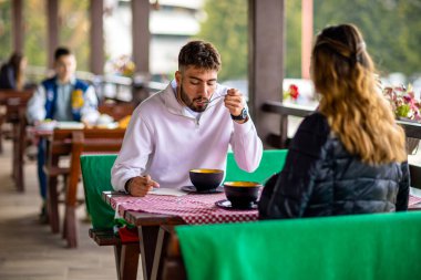 Genç çift, güneşli bir sonbahar ya da bahar günü birlikte bir dağ restoranının terasında öğle yemeği yiyorlar..