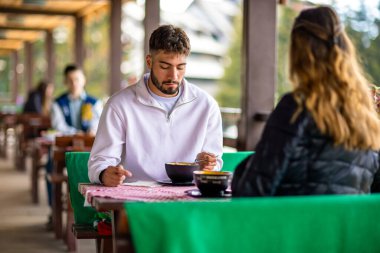 Genç çift, güneşli bir sonbahar ya da bahar günü birlikte bir dağ restoranının terasında öğle yemeği yiyorlar..