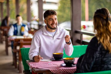 Genç çift, güneşli bir sonbahar ya da bahar günü birlikte bir dağ restoranının terasında öğle yemeği yiyorlar..