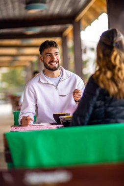Genç çift, güneşli bir sonbahar ya da bahar günü birlikte bir dağ restoranının terasında öğle yemeği yiyorlar..