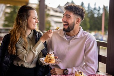 Genç çift restoranda birbirlerini kremayla besliyor.