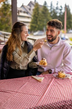 Genç çift restoranda birbirlerini kremayla besliyor.