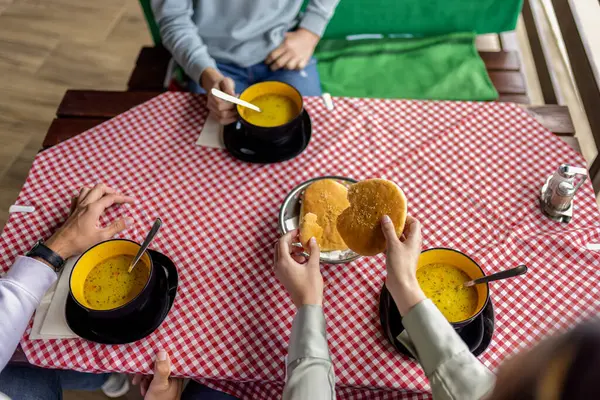 Bir dağ restoranının terasında, ahşap bir masada servis edilen üç kase sıcak çorba. 