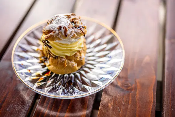 Teras masasında bir tabak kremalı profiterol.