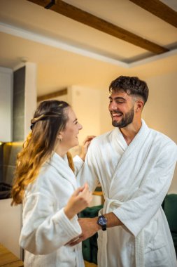 Bornoz giymiş bir çift otel odalarında dikiliyor.