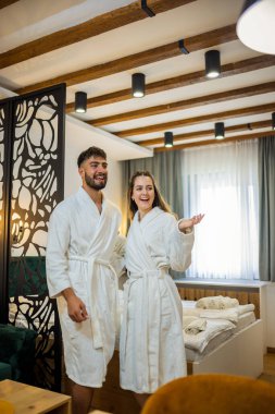 Bornoz giymiş bir çift otel odalarında dikiliyor.