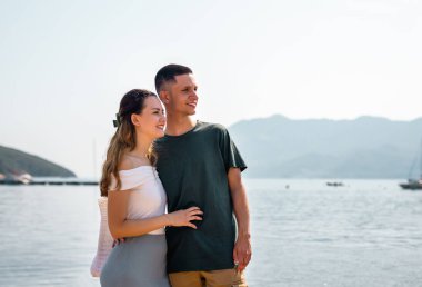 Genç bir çift sahilde birbirlerine yakın duruyorlar. Birbirlerine sımsıkı sarılıyorlar. Birbirlerine dik dik bakıyorlar..