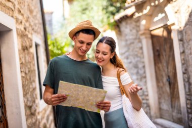 Neşeli genç bir çift yaz tatili boyunca eski bir şehrin tarihi kapısında oturur.. 