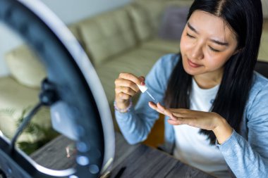 Genç bir Taylandlı güzellik etkileyicisi evde halka ışığını kullanarak bir tırnak boyama dersini filme alıyor..