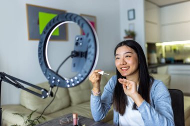 Genç bir Taylandlı güzellik etkileyicisi evde halka ışığını kullanarak bir tırnak boyama dersini filme alıyor..