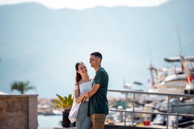 Genç bir çift marina güvertesinde yakın duruyor.