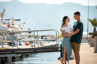 Genç bir çift marina güvertesinde yakın duruyor.