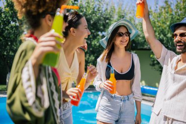  Canlı bir grup genç dans ediyor ve havuz başında eğleniyor, pipetle renkli kokteyller içiyor, mayo, şapka ve güneş gözlüğü takıyor.
