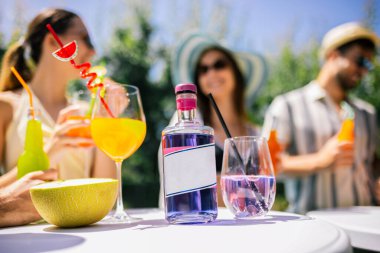 Bir grup genç havuz başında dans ediyor ve eğleniyor, pipetlerle renkli kokteyller içiyor, mayo, şapka, güneş gözlüğü takıyor ve ananas ve kavun gibi taze meyvelerle dolu bir masa hazırlıyorlar..