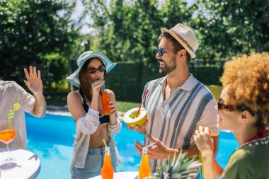 Bir grup genç havuz başında dans ediyor ve eğleniyor, pipetlerle renkli kokteyller içiyor, mayo, şapka, güneş gözlüğü takıyor ve ananas ve kavun gibi taze meyvelerle dolu bir masa hazırlıyorlar..