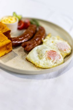 Çırpılmış yumurta, çıtır pastırma, taze domatesle servis edilmiş.