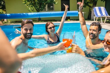 Bir grup genç arkadaş sıcak bir yaz günü havuzda eğleniyor; bir kız şamandırada, diğerleri etrafında, hepsi kokteyl içiyor ve birlikte keyifli, rahatlatıcı zaman geçiriyorlar..