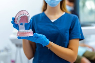 Mavi ceketli, kendine güveni tam bir dişçi. Modern diş sağlığı kliniğinde oral sağlık hizmeti veriyor..