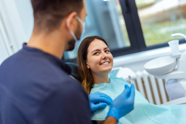 Мужчина-стоматолог, выполняющий стоматологическое лечение пациентки в современной клинике. Сосредоточьтесь на профессиональном уходе, точности и здоровье полости рта.