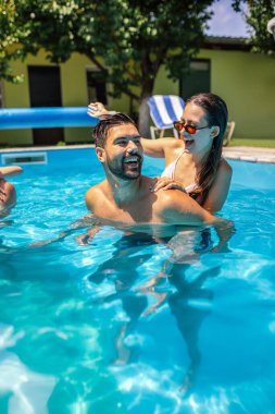 Bir grup genç arkadaş birlikte yüzme havuzunda eğleniyorlar. Güneşli bir yaz gününde gülüyor, sıçrıyor ve dinleniyor..