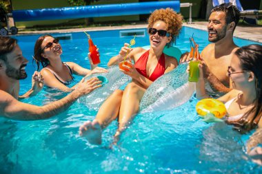 Bir grup arkadaş havuzda dinleniyorlar, renkli kokteyller içiyorlar, yaz eğlencesinin ve iyi hislerin tadını çıkarıyorlar.. 