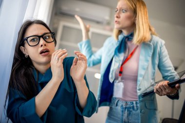 Kadın CEO ofisteki meslektaşına agresif bir şekilde bağırıyor, işyerinde gerginlik, hayal kırıklığı ve stresli bir çalışma ortamı gösteriyor..