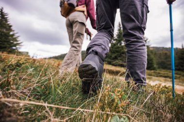 Engebeli bir dağ yolunda yürüyüş botlarının yakın görüntüsü, nefes kesen doğa ve aşağıdan görünen dağlar..