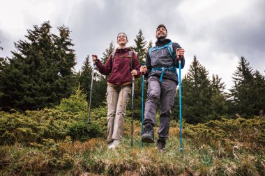 Tam teçhizatlı erkek ve kadın yürüyüşçüler nefes kesen doğa tarafından sarılmış botlar, sırt çantaları ve ceketler giyerek çarpıcı dağların içinden geçiyorlar..