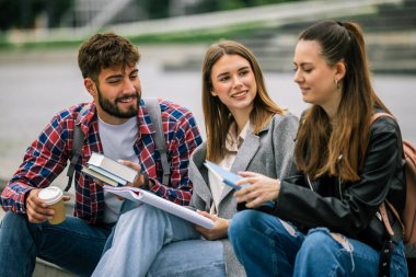 Üniversite kampüsünde üç üniversite öğrencisi birlikte okuyorlar.