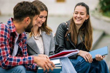 Üniversite kampüsünde üç üniversite öğrencisi birlikte okuyorlar.