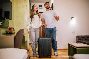 Genç bir çift otel odasına bavullarıyla giriyor, gezilerinde güzel bir şekilde hazırlanan odadan etkileniyor ve memnun kalıyorlar..