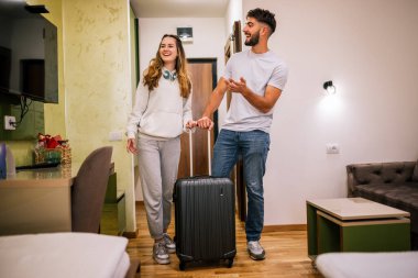 Genç bir çift otel odasına bavullarıyla giriyor, gezilerinde güzel bir şekilde hazırlanan odadan etkileniyor ve memnun kalıyorlar..