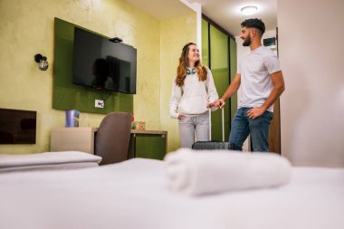 Genç bir çift otel odasına bavullarıyla giriyor, gezilerinde güzel bir şekilde hazırlanan odadan etkileniyor ve memnun kalıyorlar..