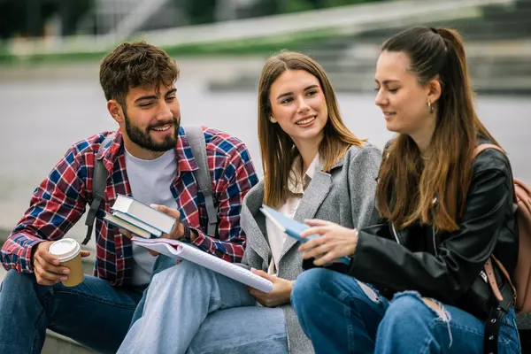 Üniversite kampüsünde üç üniversite öğrencisi birlikte okuyorlar.