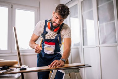 Tam teçhizatlı bir tamirci çekiçle bir dairede döşeme kaplaması, hassas kurulum ve yüksek kalitede işçiliği garantiliyor..