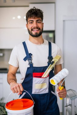 Bir dairedeki ressam, duvarları boyamaya hazırlanıyor, elinde kireç ve fırça tutuyor, yenilenmeye hazır..