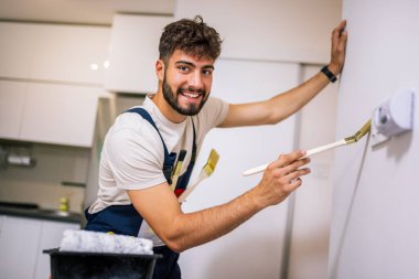 Bir dairedeki ressam, fırçalı duvarlara kireç sürüyor, yeni ve hassas bir iç yenileme üzerinde çalışıyor..